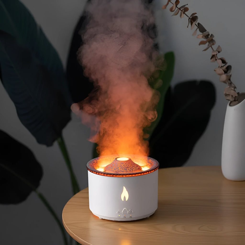 White and blue volcano-shaped tabletop humidifier emitting a mist, with mechanical controls and a UK plug adaptor.