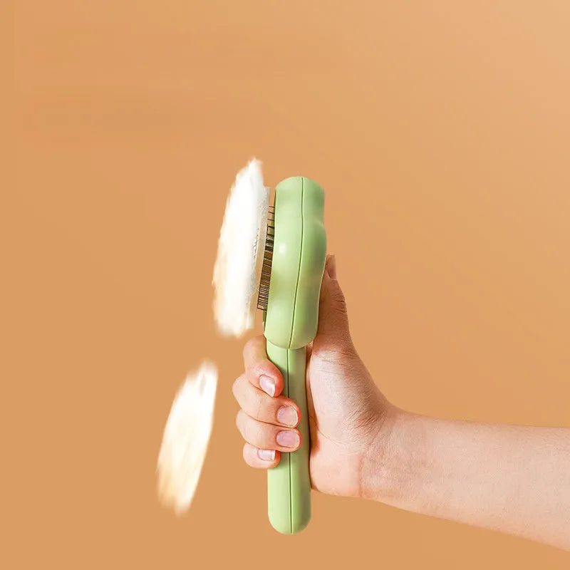 Green self-cleaning cat comb with stainless steel pins on a white background