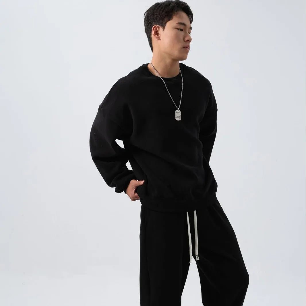 Men's black polar fleece sports suit with crew neck coat and matching trousers on a hanger.