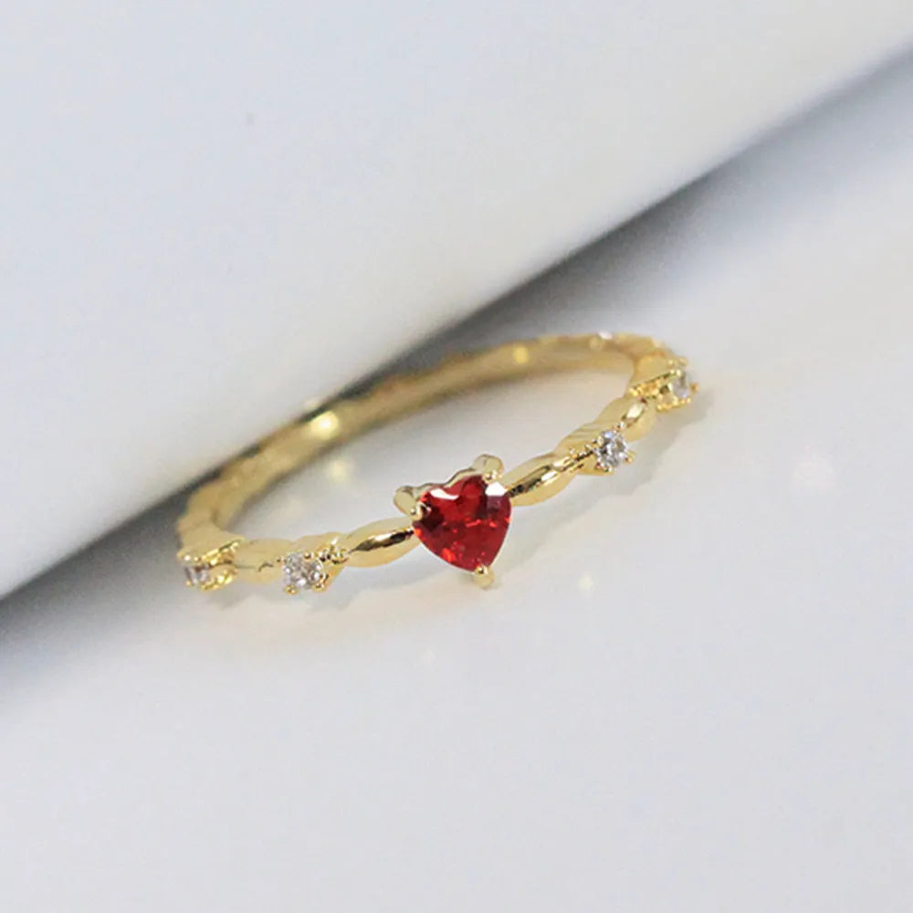 Gold or silver tone peach heart fashion ring with a zircon stone on a model finger.