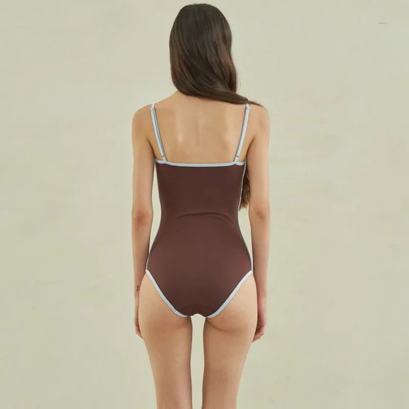 Brown women's one-piece swimsuit with triangle style on a hanger.