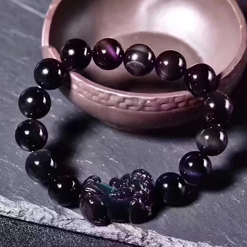 Natural ice colour eye obsidian crystal bracelet on a wrist, showing polished beads.
