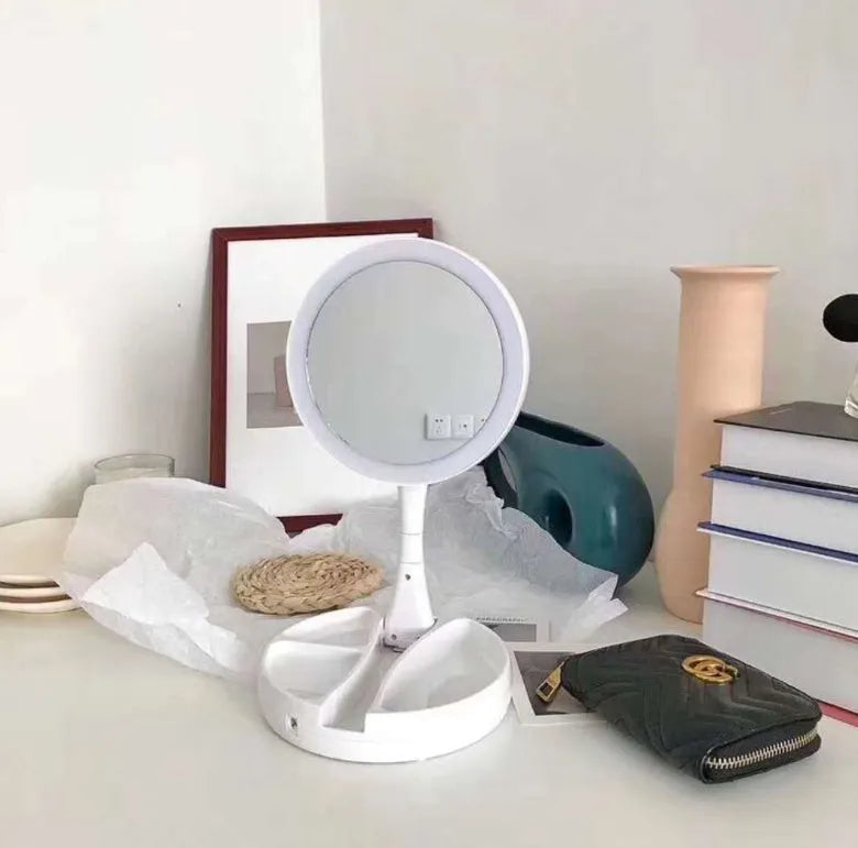 White acrylic foldable LED vanity mirror with USB charging port and double-sided design on a table