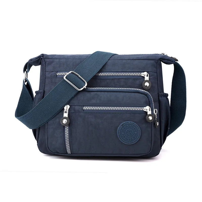 Grey nylon messenger bag with single shoulder strap showing square vertical shape and lining interior