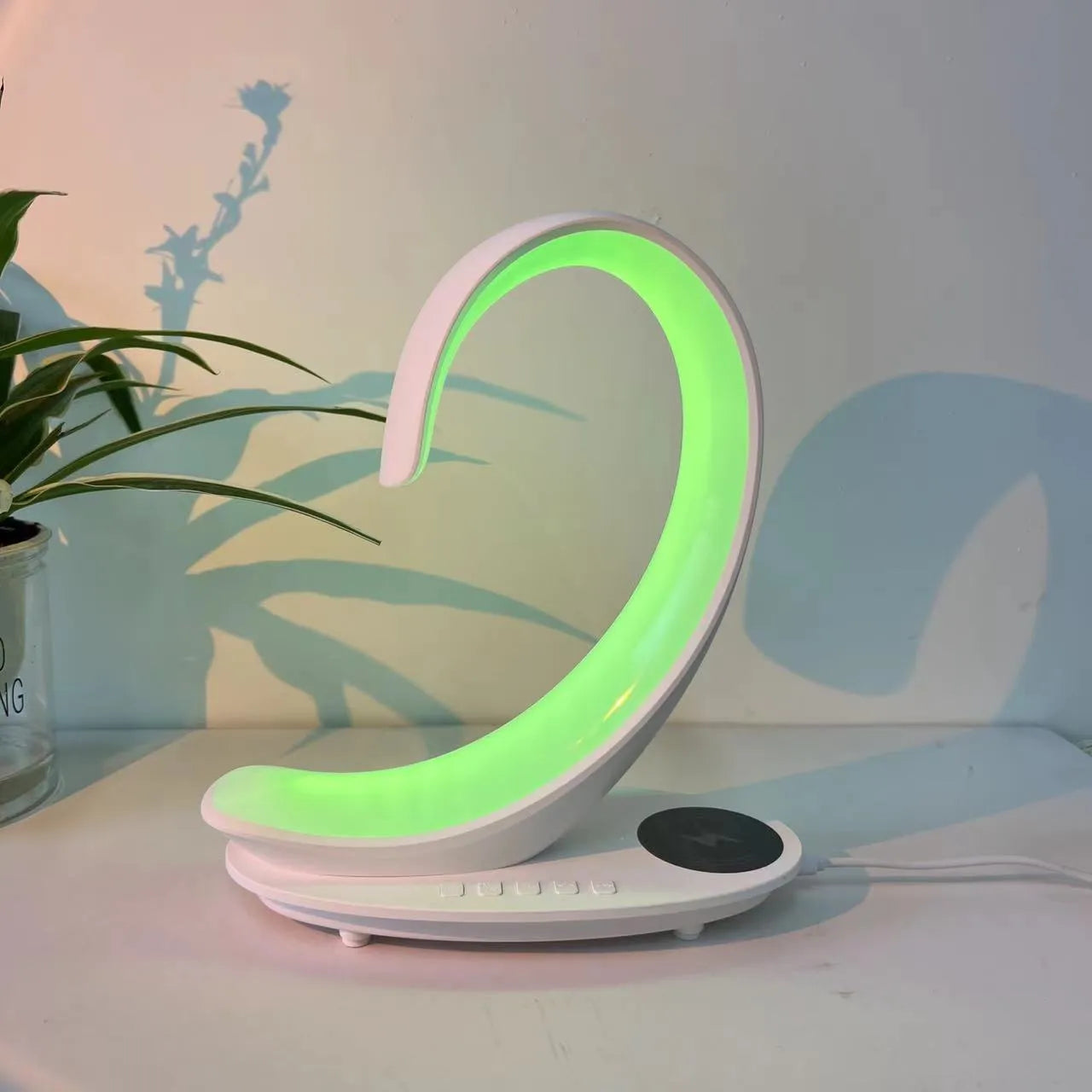 White swan-shaped desktop device with wireless charging pad, Bluetooth speaker, and colourful atmosphere lighting.