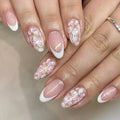 Short almond-shaped false nails with French style base and glitter powder flower decoration, colour C625.