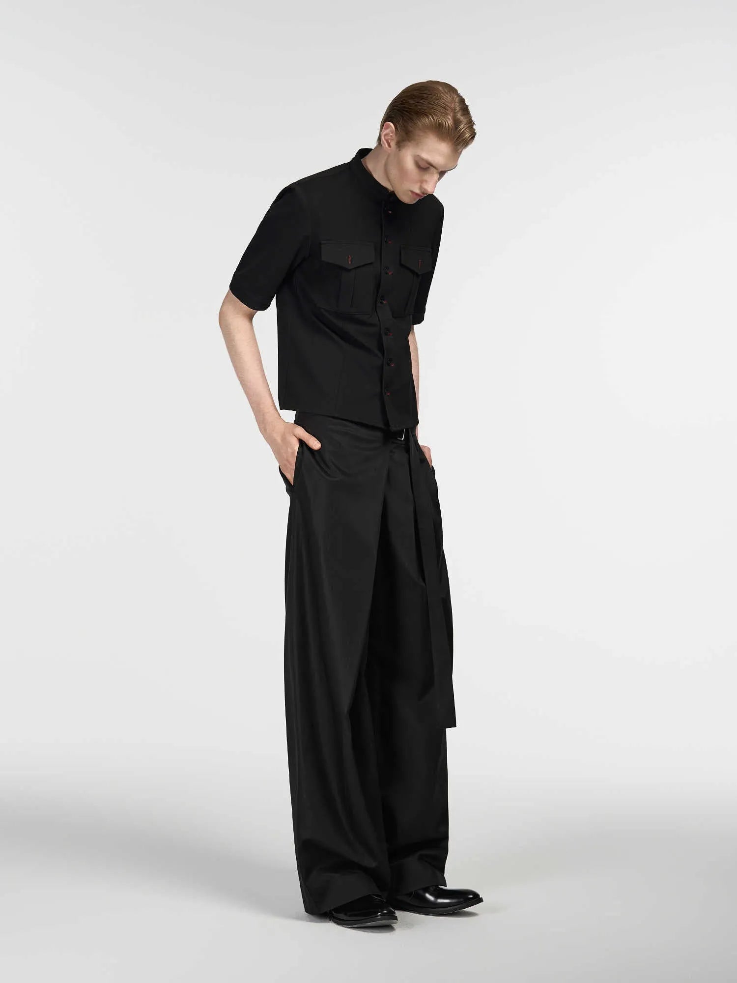 Black straight-leg trousers with a single front pleat and adjustable waistband on a hanger.