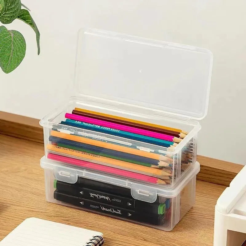 Transparent plastic stationery storage box containing pencils, colour leads, and art supplies