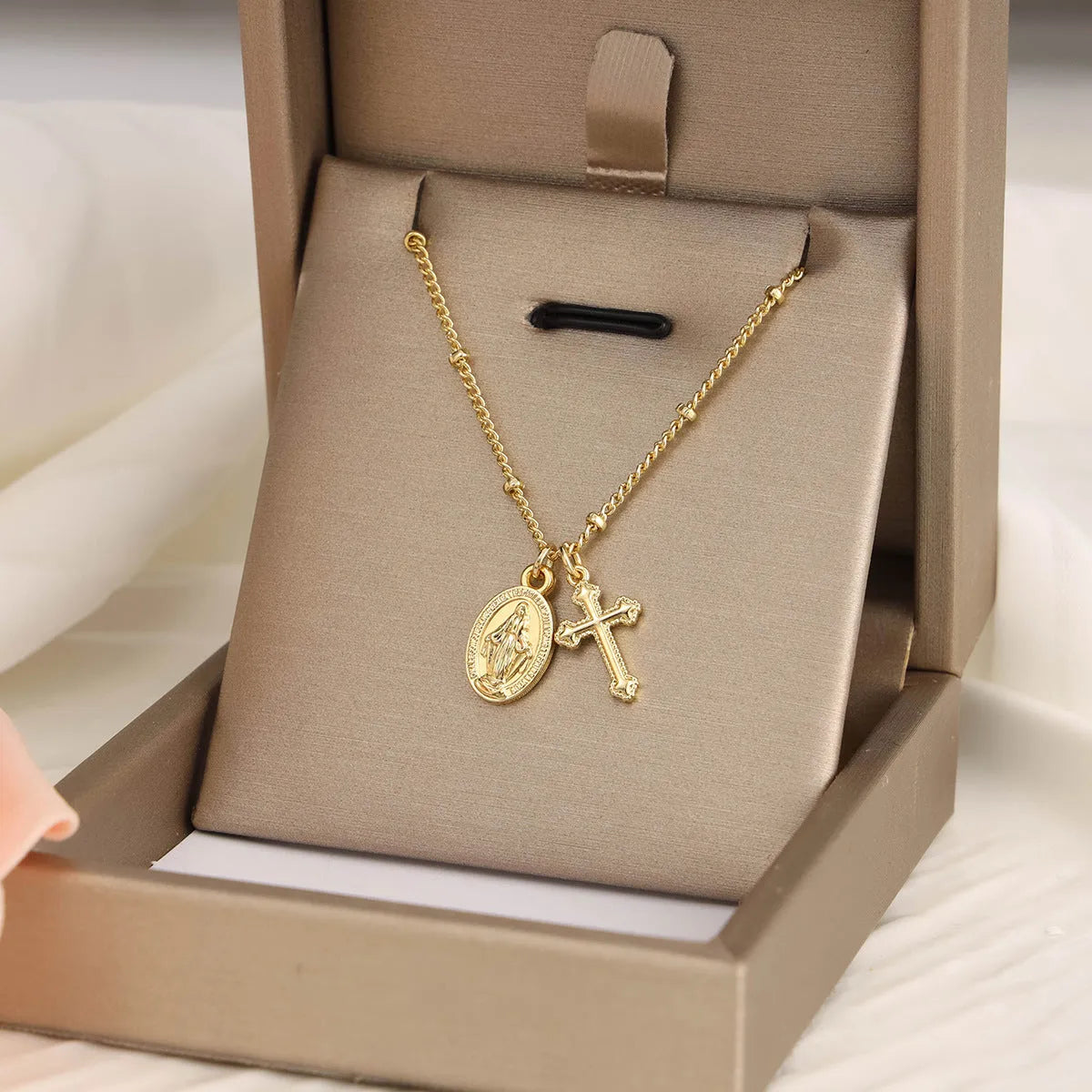Gold coloured geometric cross Virgin Mary pendant necklace on a chain.