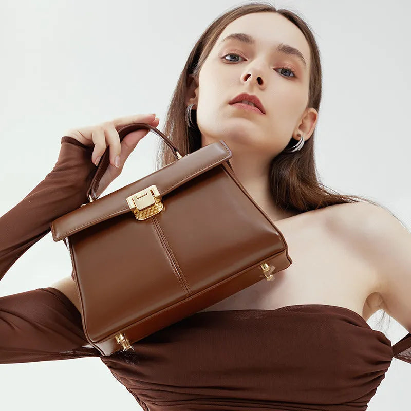 Women's black leather shoulder bag with vachette clasp showing internal zippered pocket