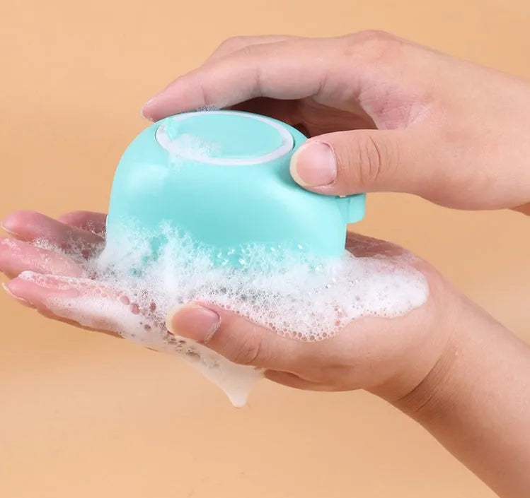 Blue silicone dog bath brush with soft bristles, shown on a hand.