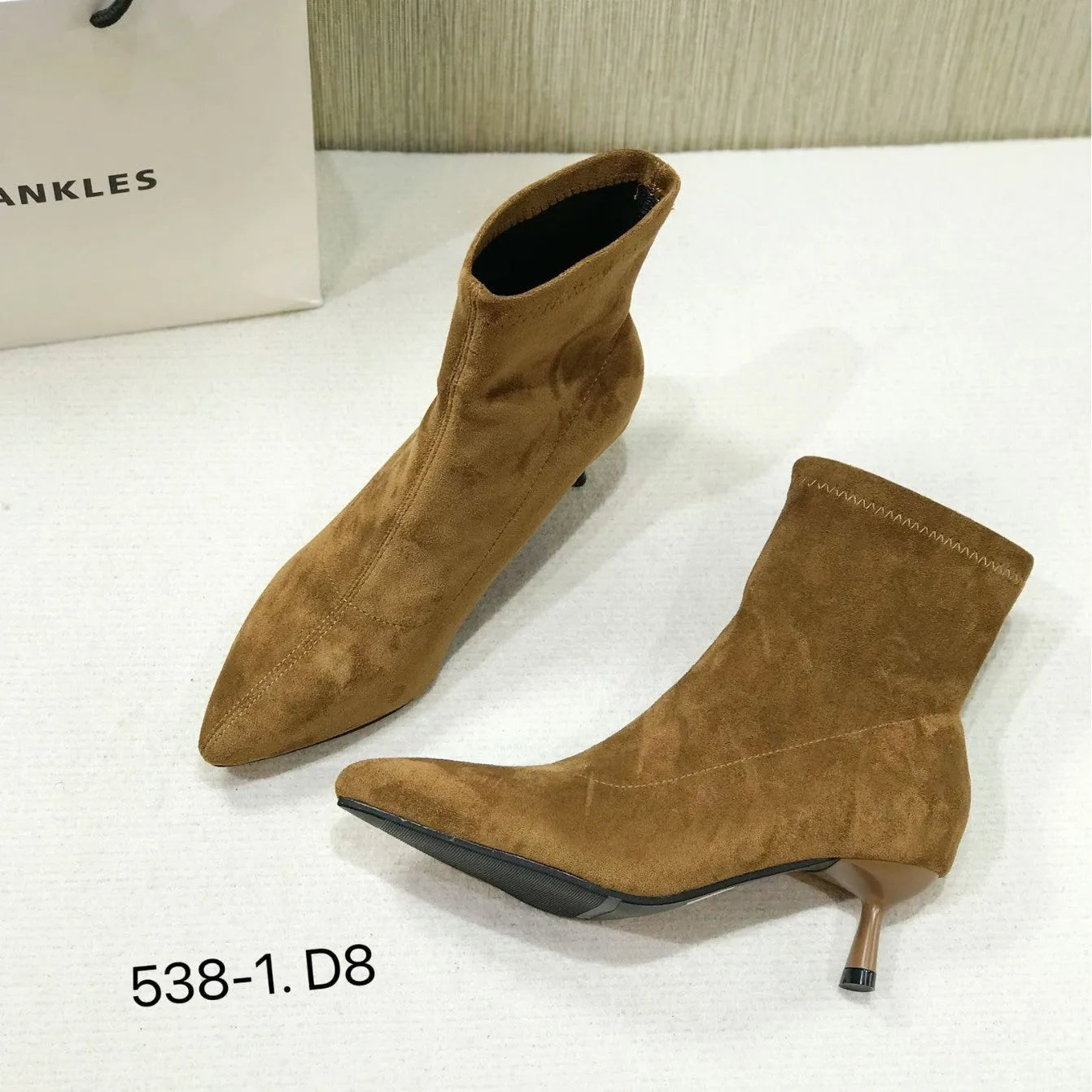 Black pointed toe women's ankle boots with a stiletto heel on a plain background