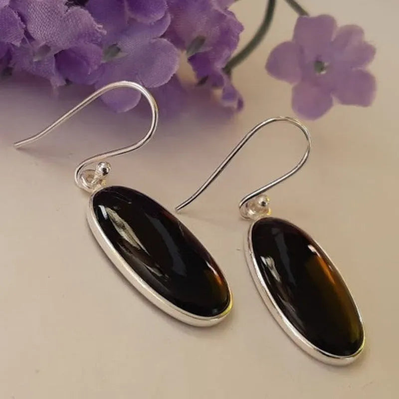 Close-up of women's geometric earrings with oval black agate pendant in silver electroplated setting.