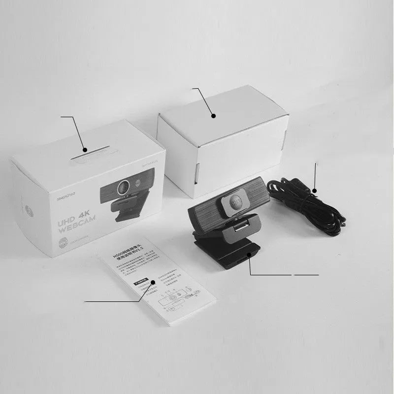 Black USB webcam with magnetic privacy cover on a desk next to a laptop