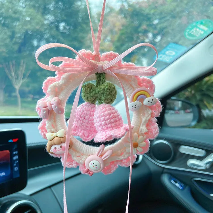 Handwoven wool bell orchid flower car pendant on a green background.
