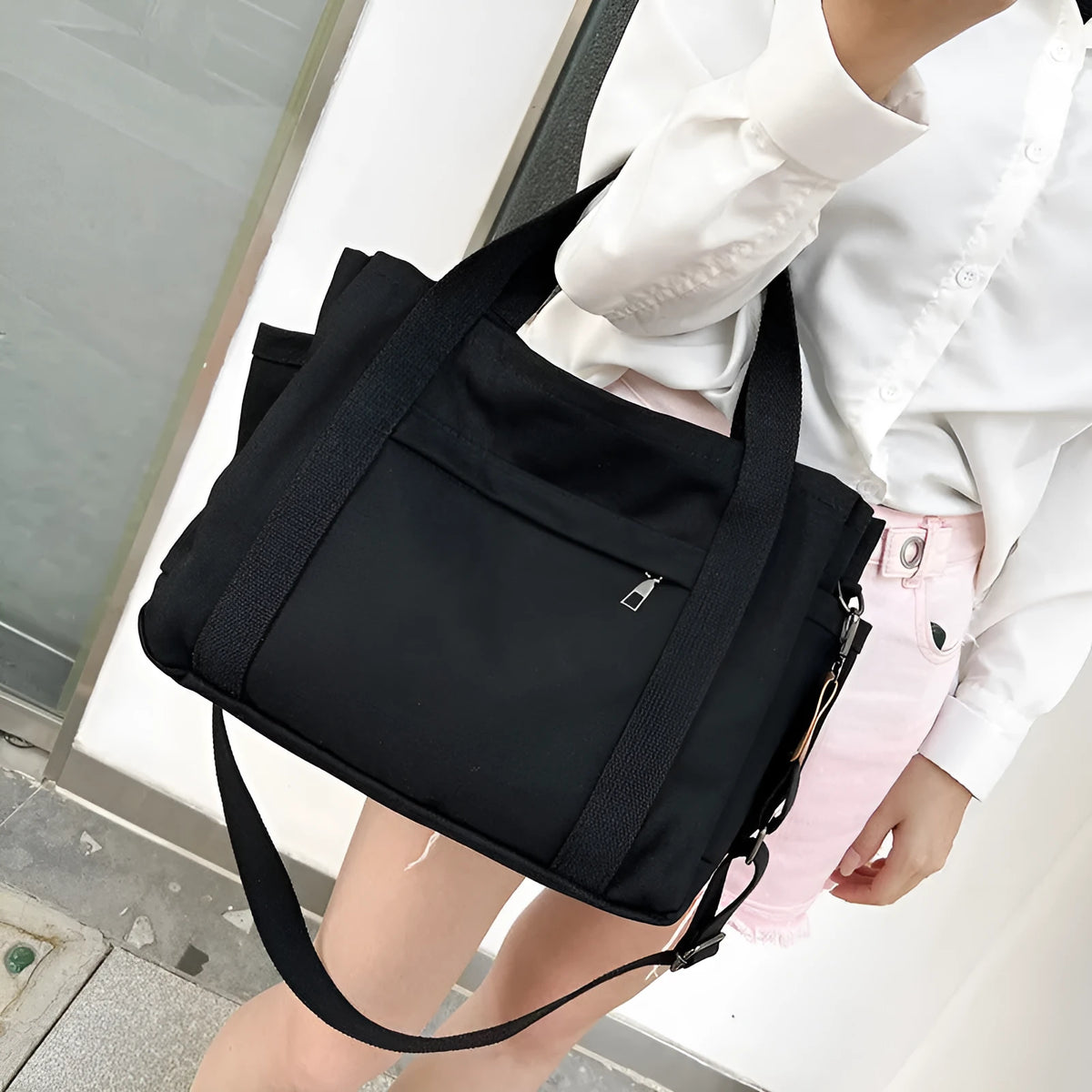 Large horizontal square canvas tote bag with crossbody strap and multiple internal pockets.