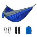 Blue nylon parachute cloth camping hammock hung between two trees.