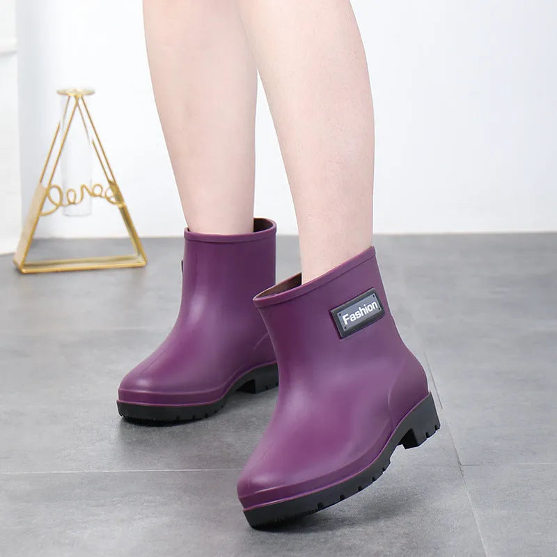 Women's black PVC mid-calf rain boot with a low heel on a wet surface.