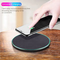 Black Qi wireless charging pad for iPhone 11 on a wooden desk