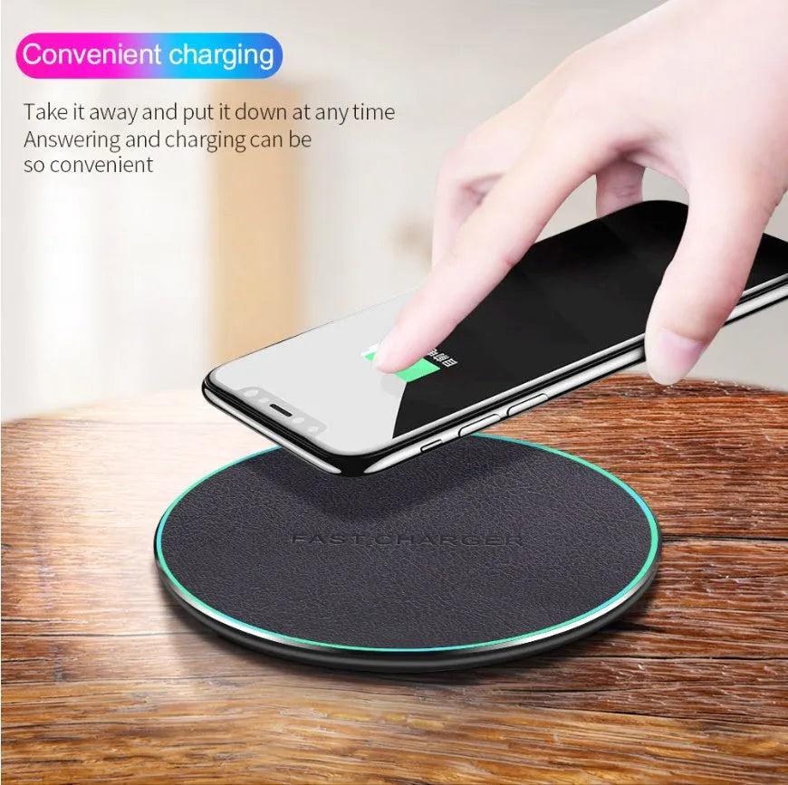 Black Qi wireless charging pad for iPhone 11 on a wooden desk