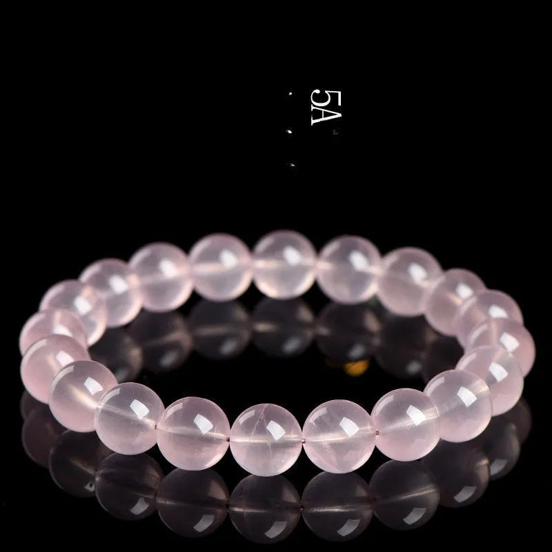 A pink crystal bead bracelet with polished round stones on a single strand.