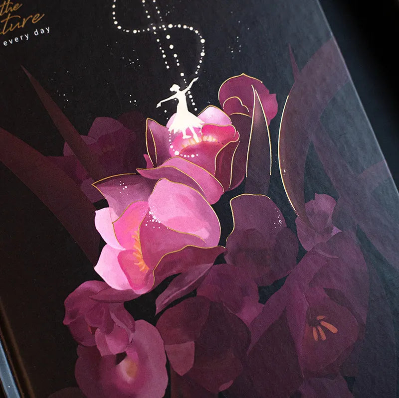 A5 notebook with luminous holographic cover lying flat, showing colourful illustrated interior pages.