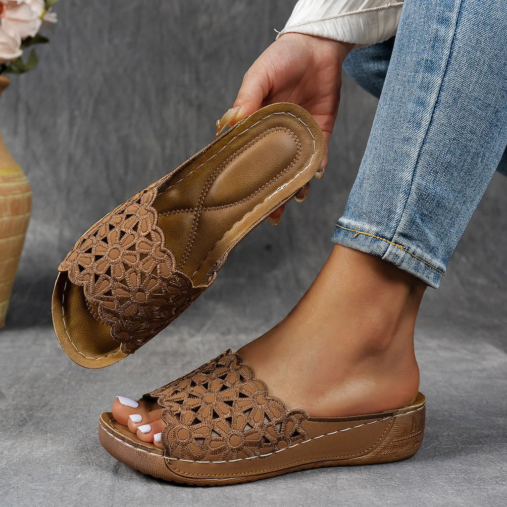 Women's wedge beach slippers with flower cutout design in black colour showing fish mouth toe shape
