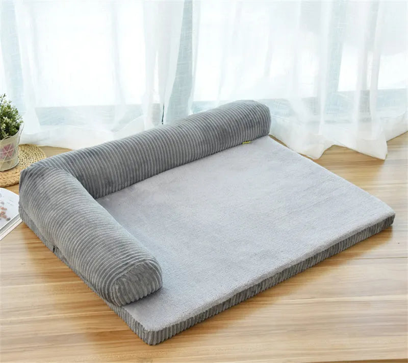 Corduroy pet sofa dog bed with a raised bolster, shown in a grey colour on a wooden floor.