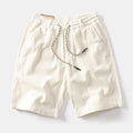 Men's khaki retro cargo shorts with a straight leg on a summer streetwear backdrop.