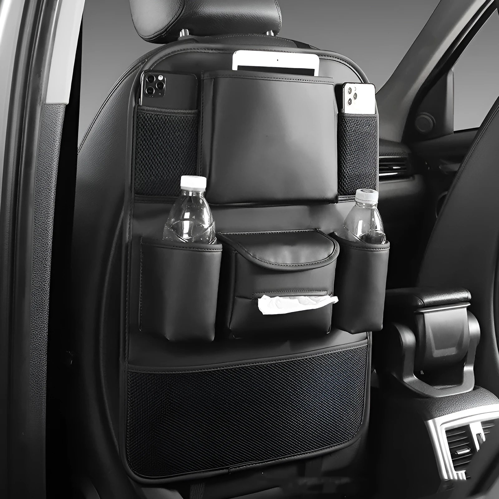 Synthetic leather car seat back storage bag hanging on the back of a grey car seat.