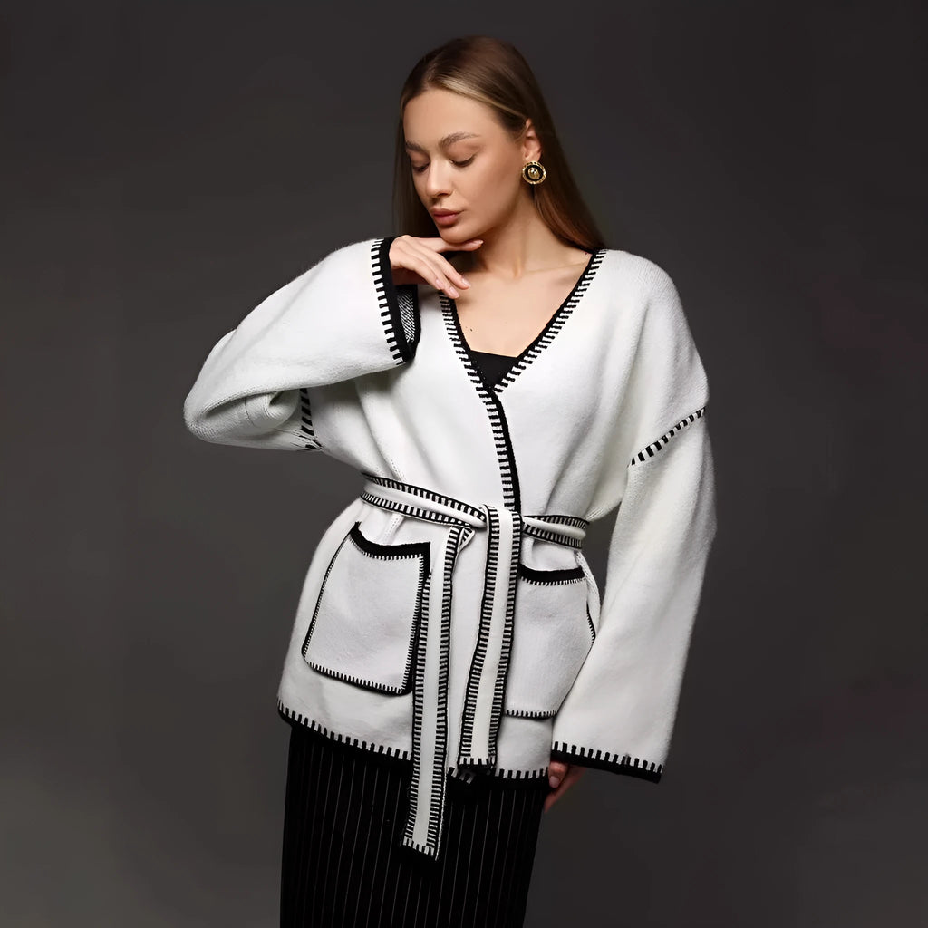 Loose mid-length knitted cardigan sweater coat with a lace-up front, shown in a neutral colour.