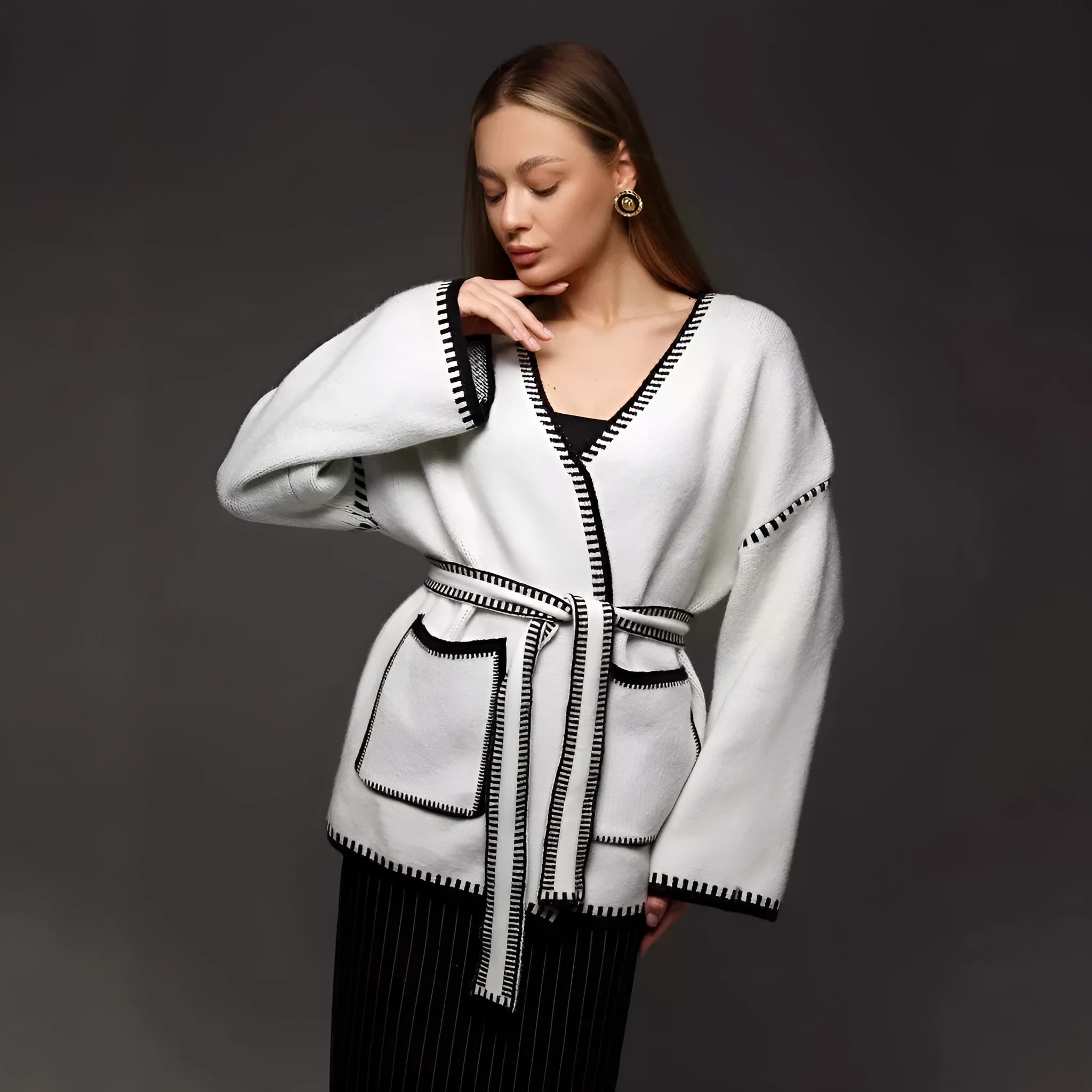 Loose mid-length knitted cardigan sweater coat with a lace-up front, shown in a neutral colour.