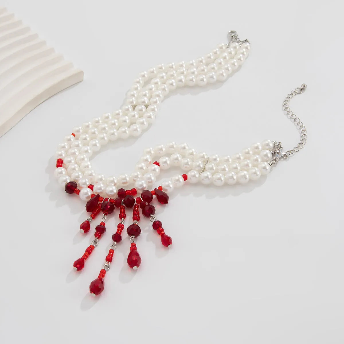 Men's Halloween necklace with red artificial crystal blood drop pendant and black imitation pearl tassels on a metal chain.