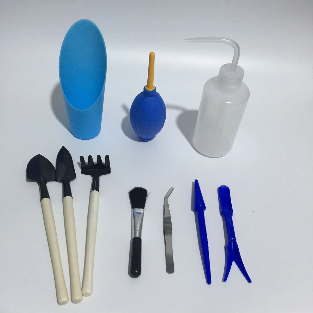 Succulent gardening tool set showing mini shovel, drip kettle, tweezers, and brush for indoor plants.