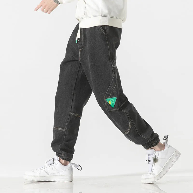 Man wearing grey loose-fit tapered cotton trousers with a mid-rise waist.