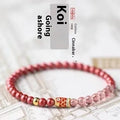 Purple cinnabar and strawberry quartz bracelet with peach blossom and koi charms on a wrist.