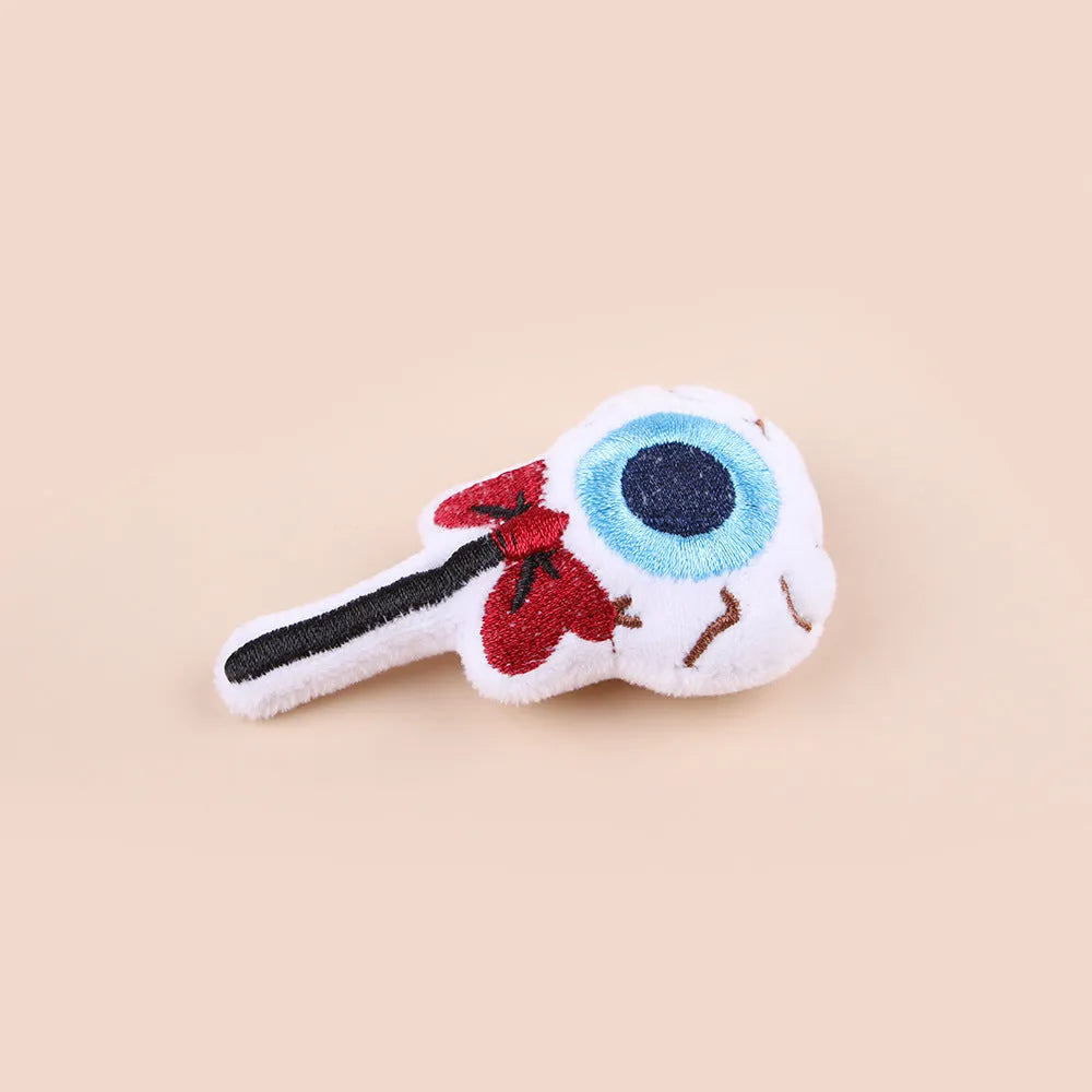 Small plush cat teaser toy in candy, eyes, and skull designs on a blue background.