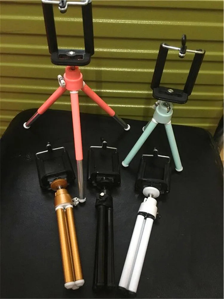Black desktop phone holder with a two-section adjustable bracket arm holding a mobile phone.