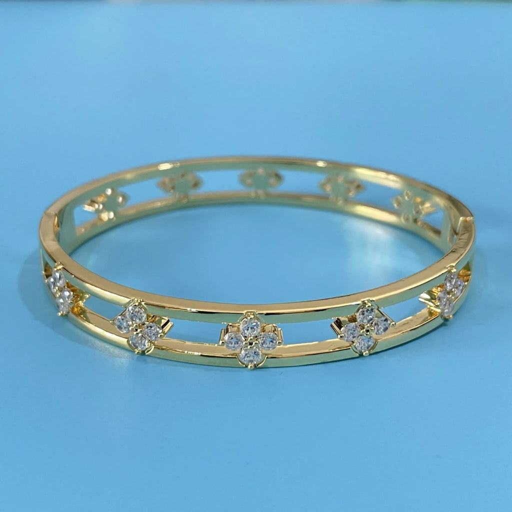 Gold and silver hollow women's bracelets with four-leaf clover zircon charms on a white background.