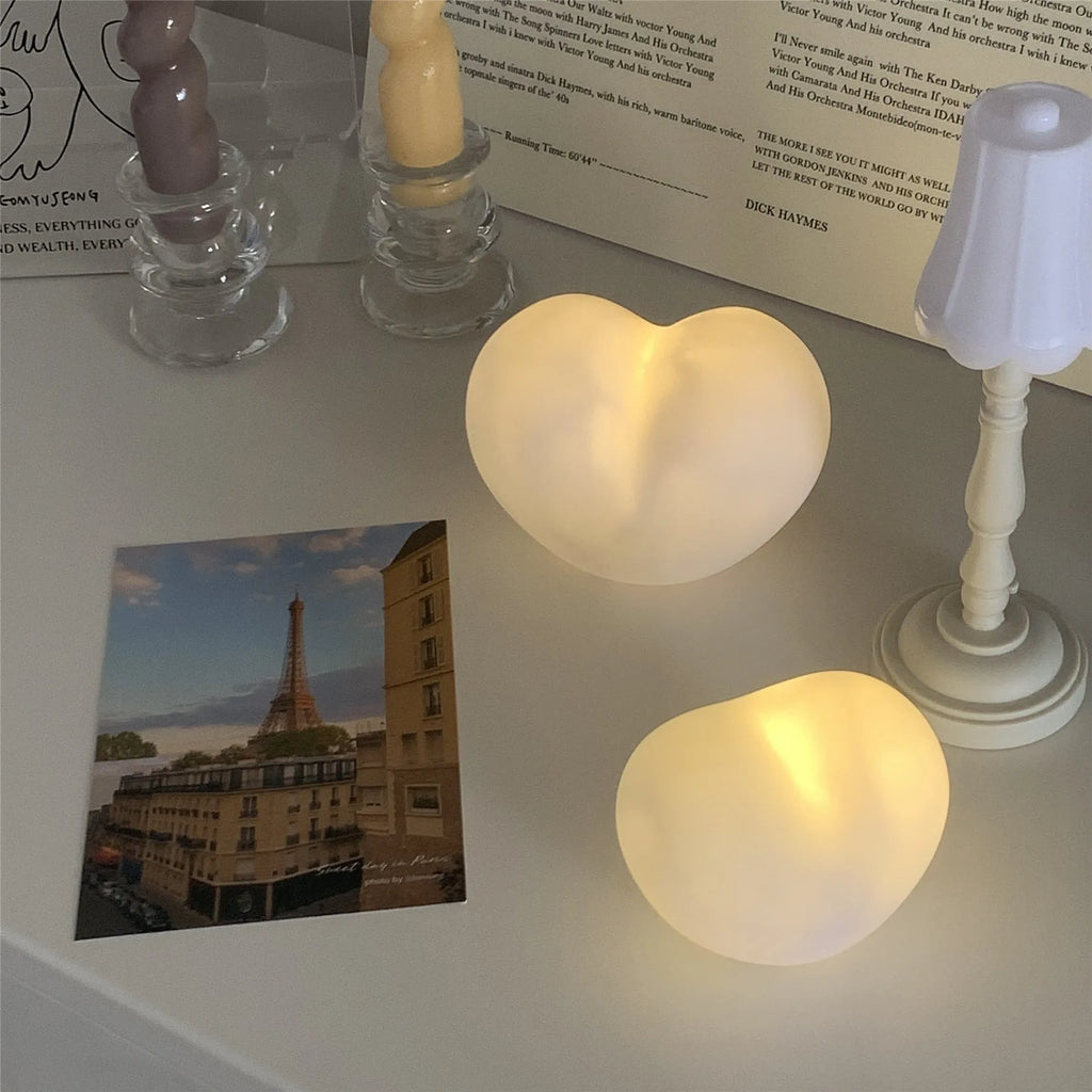 White and pink vinyl love-shaped atmosphere lamps in two sizes on a shelf.