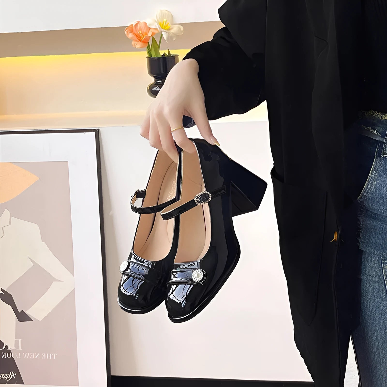 Women's black patent leather round toe high heels with a chunky heel and buckle strap, shown on a foot.