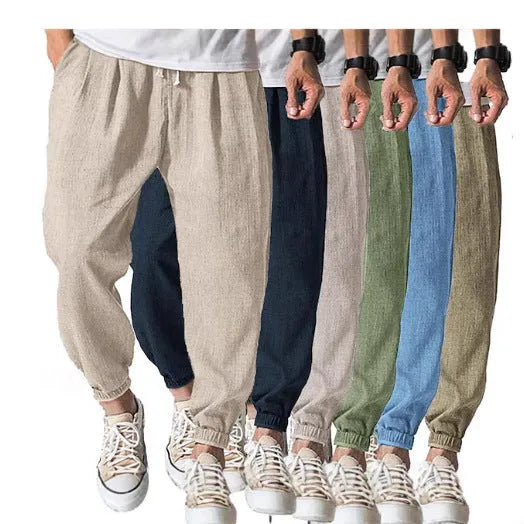 Man modelling loose fit cotton trousers with elasticated ankle cuffs in a light green colour.
