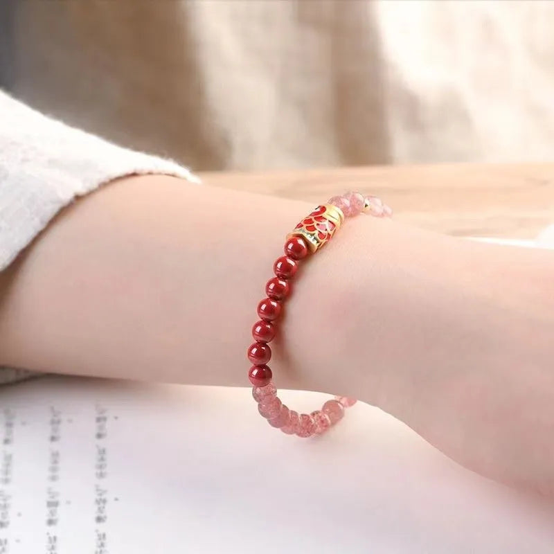Purple cinnabar and strawberry quartz bracelet with peach blossom and koi charms on a wrist.