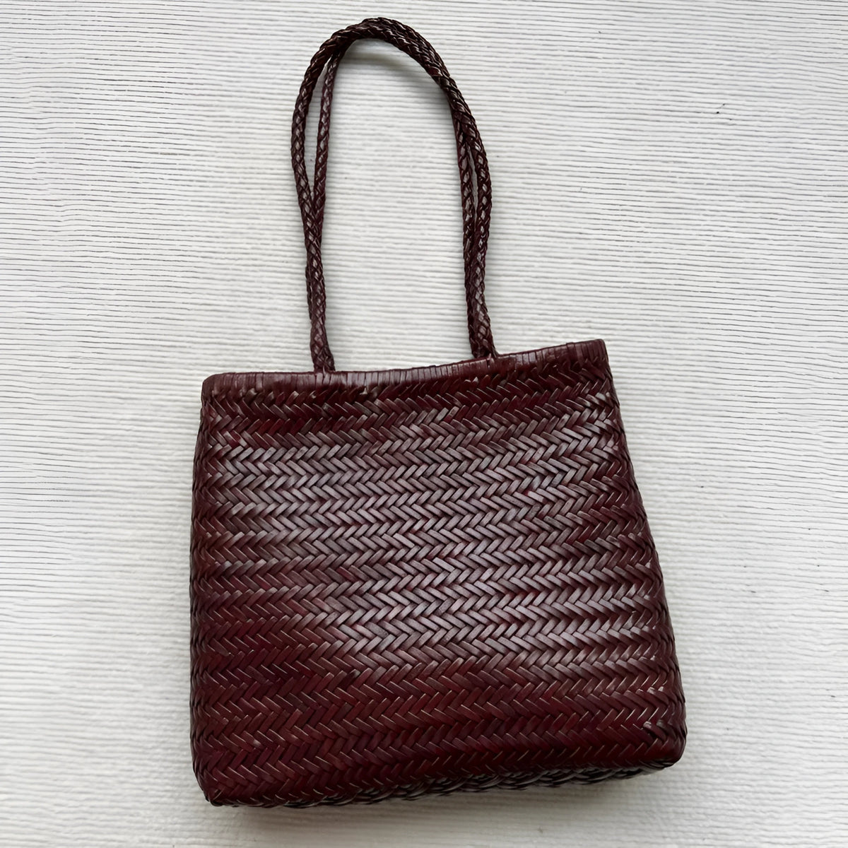 Brown woven genuine leather tote bag with a three-dimensional front pocket.