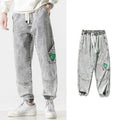 Man wearing grey loose-fit tapered cotton trousers with a mid-rise waist.