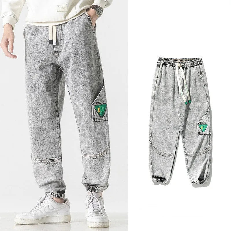 Man wearing grey loose-fit tapered cotton trousers with a mid-rise waist.