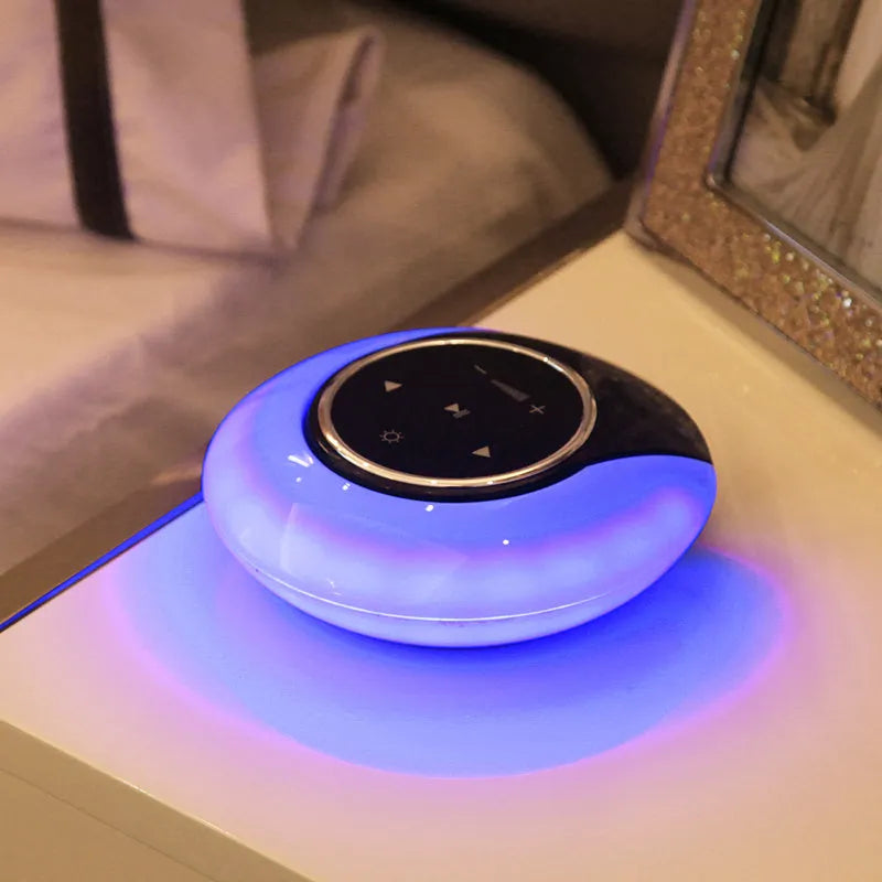 Foldable blue and white Bluetooth desk lamp with speaker, showing touch controls on a desk.