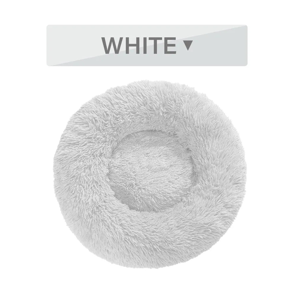 Fluffy donut-shaped dog bed in long plush material, showing raised rim and central cushion.