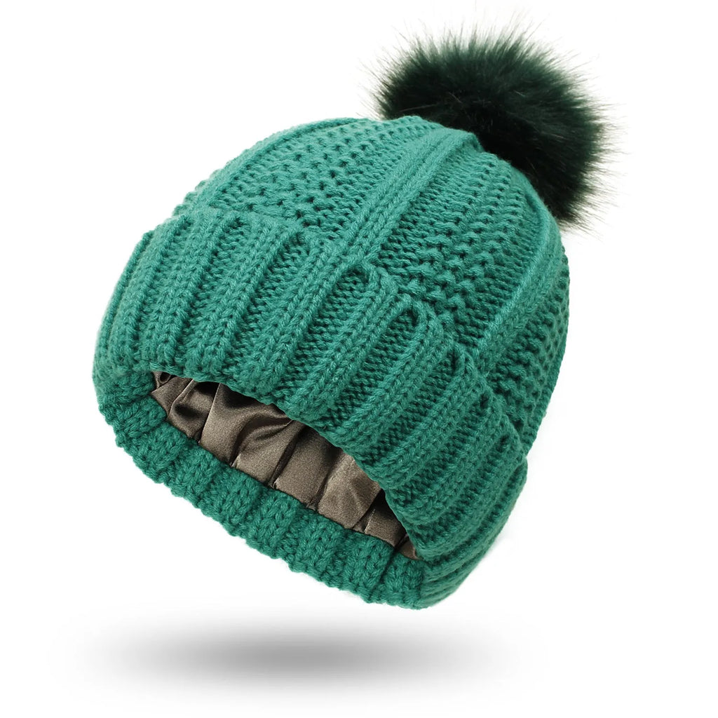 Women's black wool knit beanie with satin lining and a white faux fur pom pom