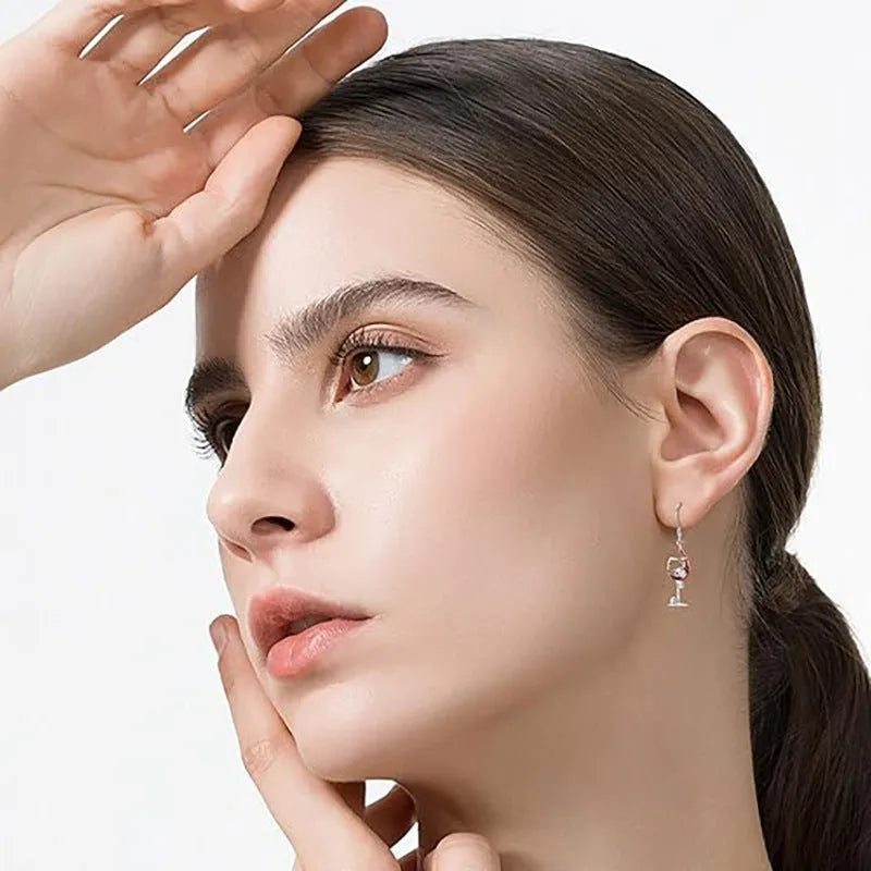 A pair of silver-toned zinc alloy earrings shaped like wine glasses adorned with skull details, on a plain background.